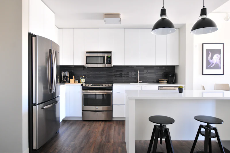 White kitchen with a dark tile backsplash and wood-look floors