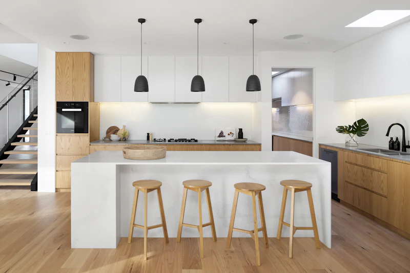 Bright kitchen with flat-panel white cabinets, a long island and wood stools