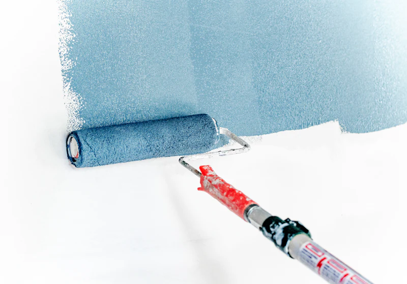 Paint roller rolling fresh color onto a white wall