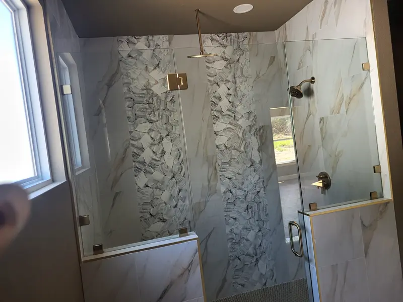 Walk-in shower with marble-look tile and a frameless glass enclosure