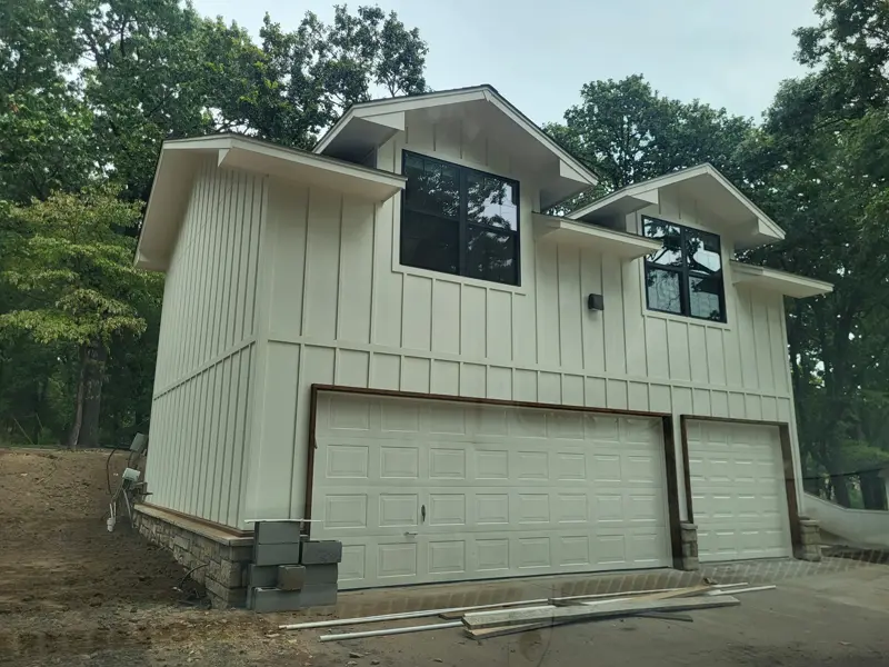 Two-story garage finished in cream board-and-batten siding with black windows