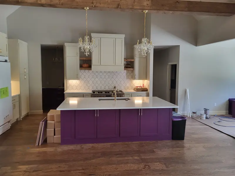 Kitchen with light shaker cabinets, a patterned backsplash and a plum-colored island