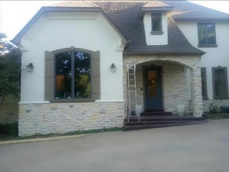 Stucco and stone home with an arched entry, a large arched window and a ladder at the porch